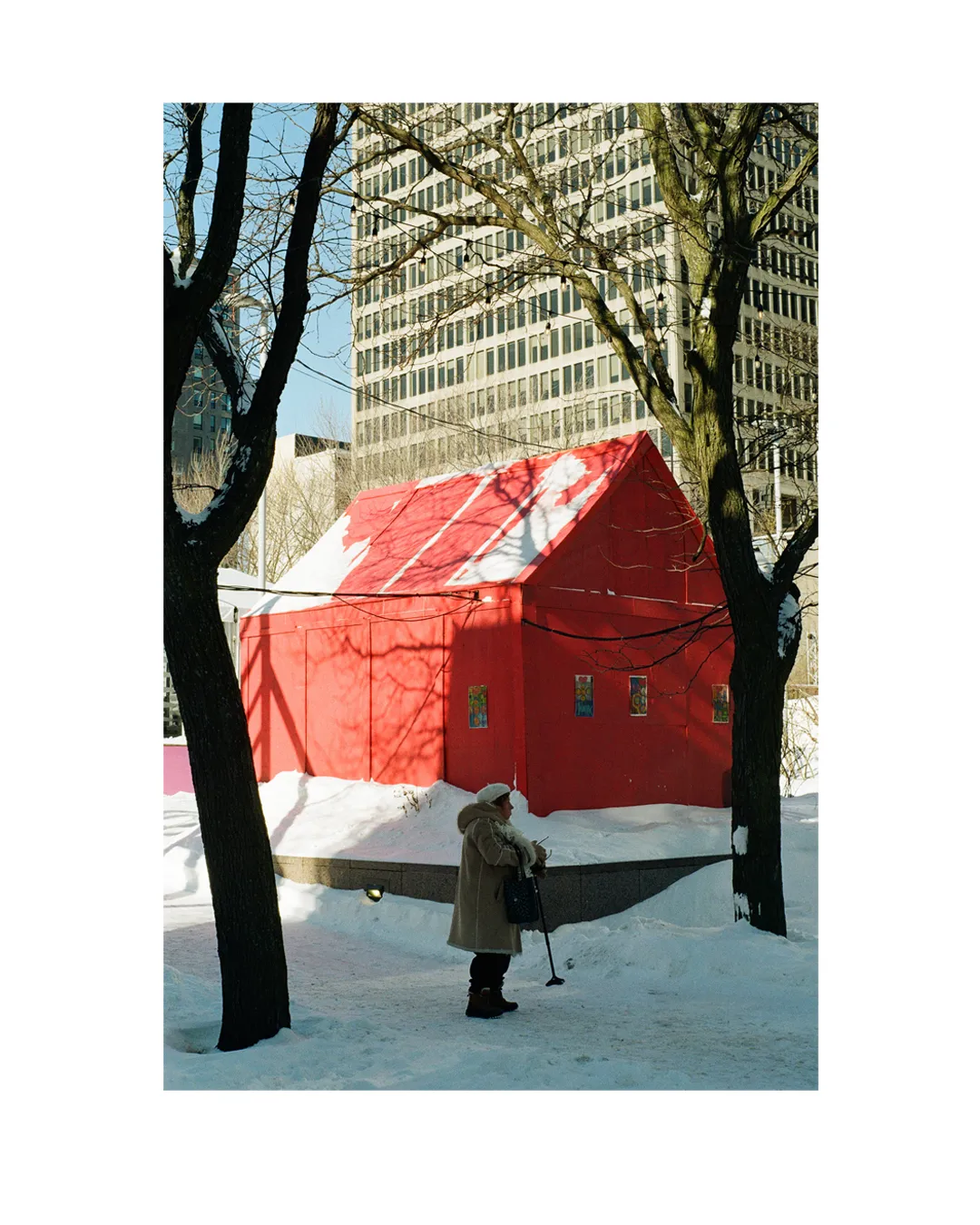 elderly lady standing in front of a red house